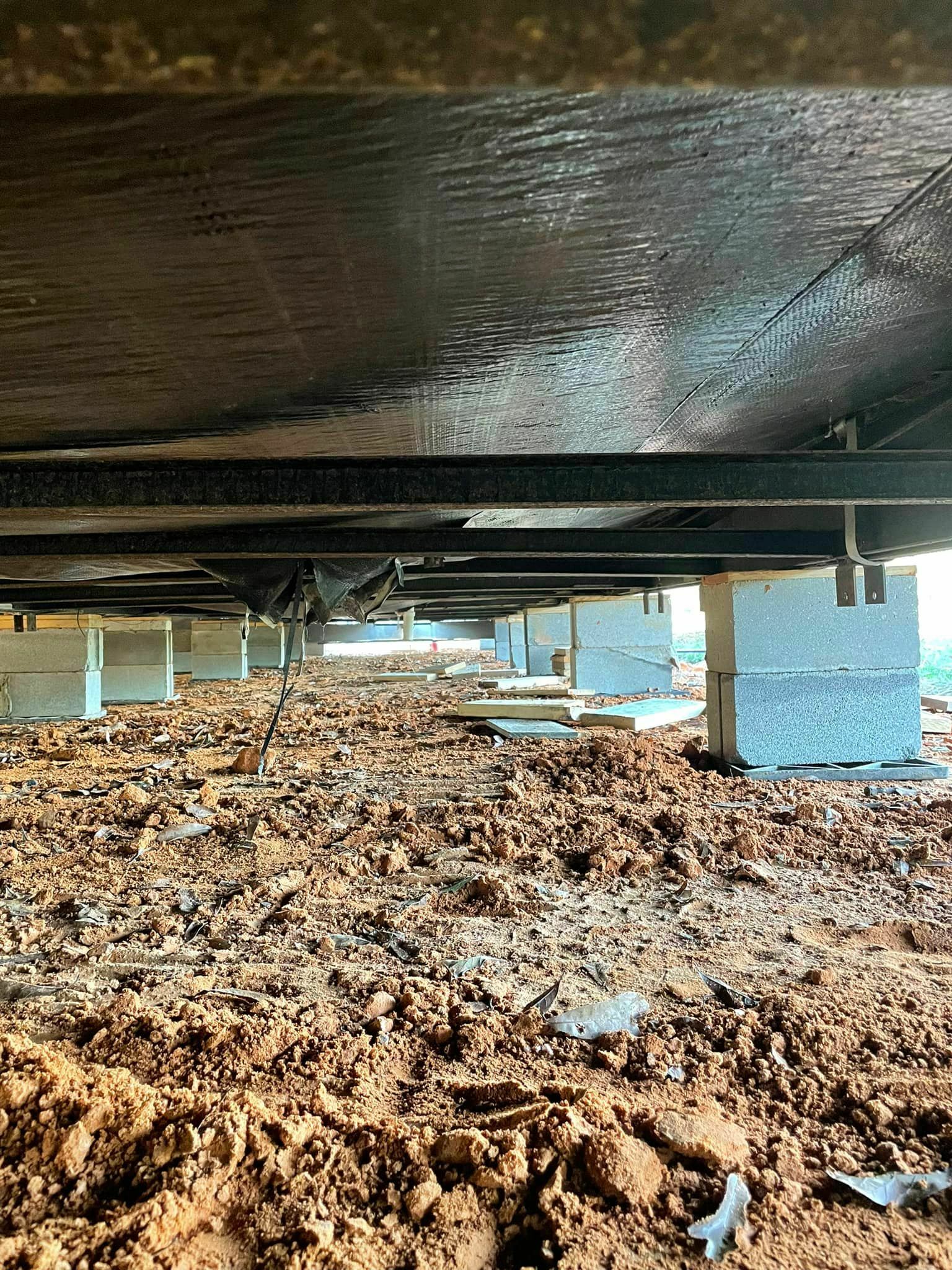 Crawl space under a manufactured home with freshly installed concrete block supports in East Texas.