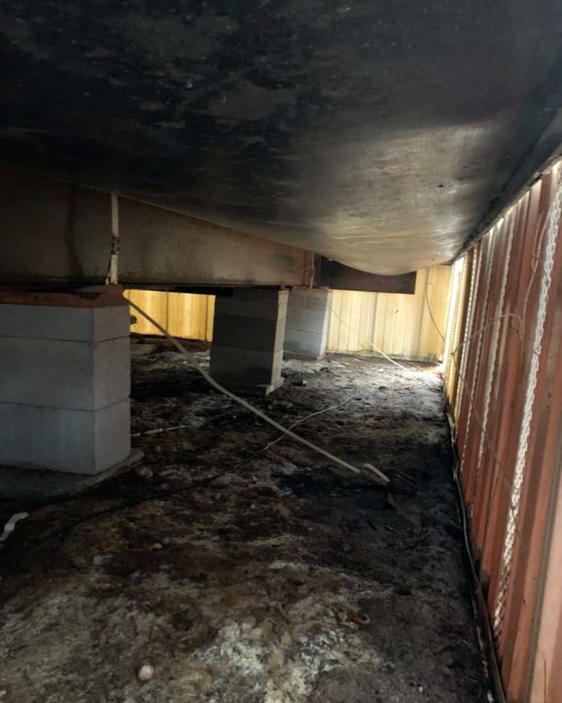 Crawl space under a manufactured home in Gilmer, TX showing concrete block supports and structural bracing.