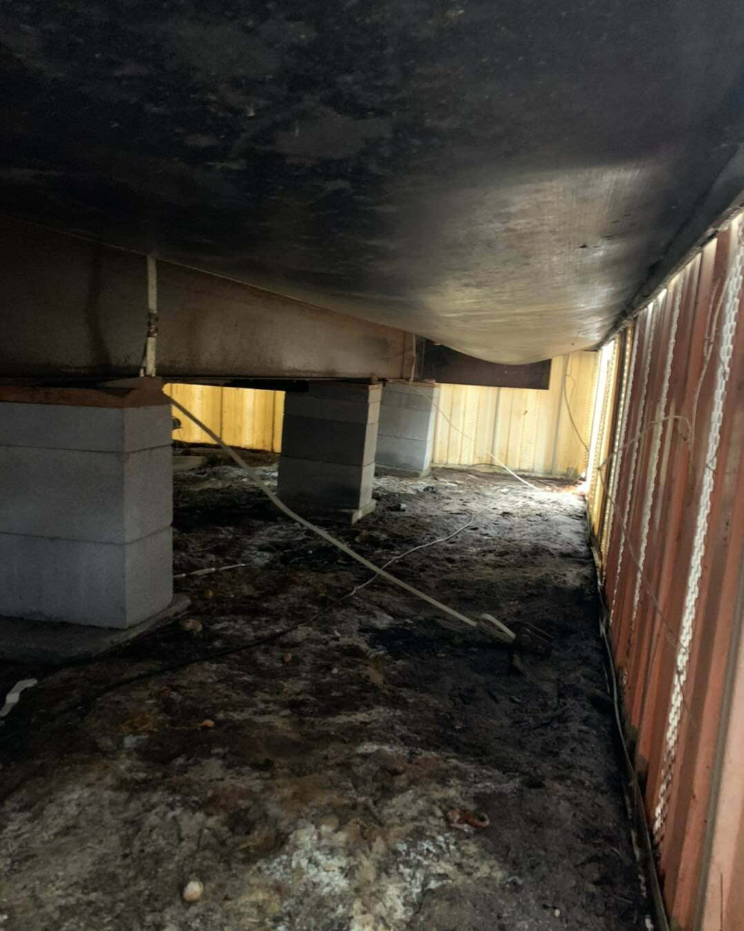Crawl space under a manufactured home in Gilmer, TX showing concrete block supports and structural bracing.