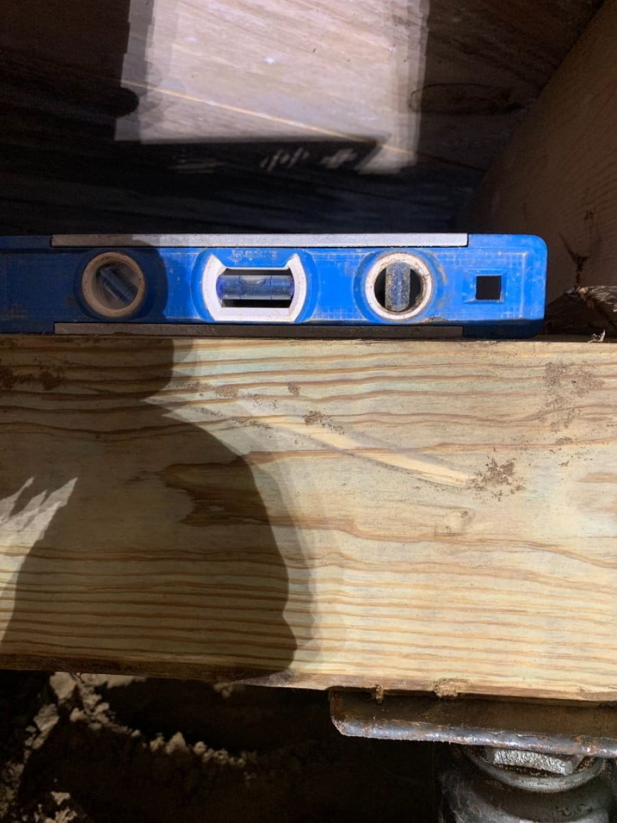 Leveling tool placed to measure and adjust foundation alignment during repairs in East Texas.