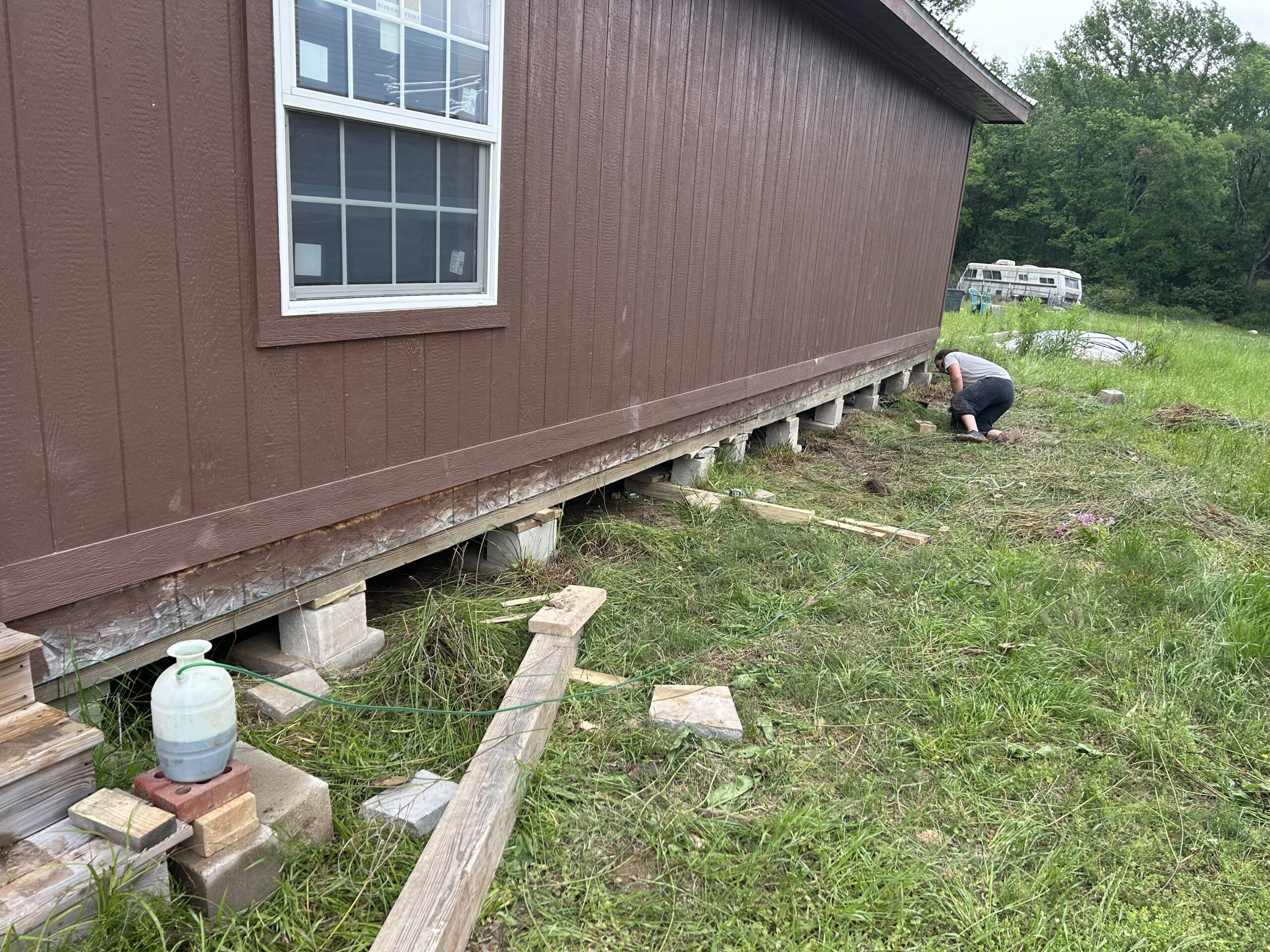 Technician inspecting and adjusting block piers under a manufactured home during leveling work in East Texas.