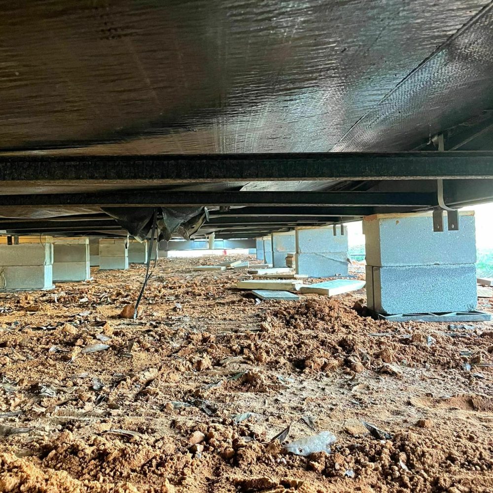 Crawl space under a manufactured home with freshly installed concrete block supports in East Texas.